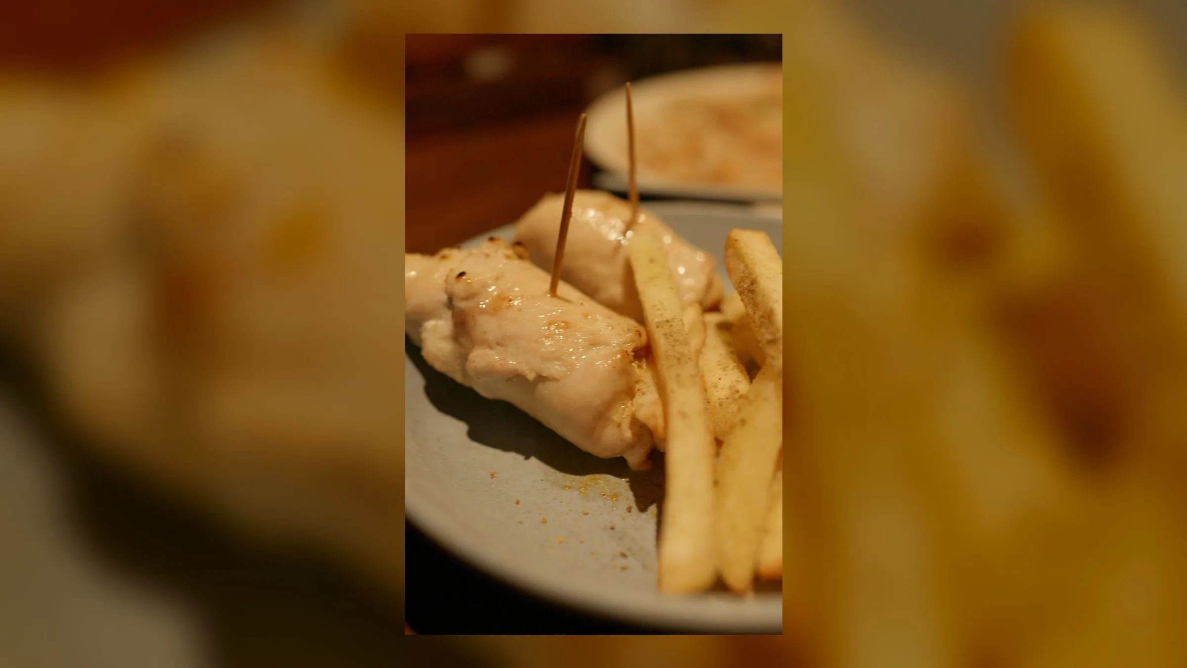 A plate of grilled chicken skewers served with a side of golden fries